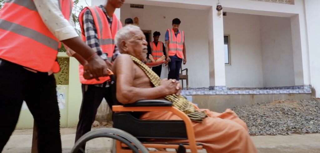 An elderly man is pushed in a wheelchair